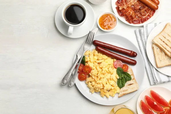 Lezzetli bir kahvaltı. Hafif ahşap masada servis edilen sosis ve domatesli nefis çırpılmış yumurta. Metin için boşluk