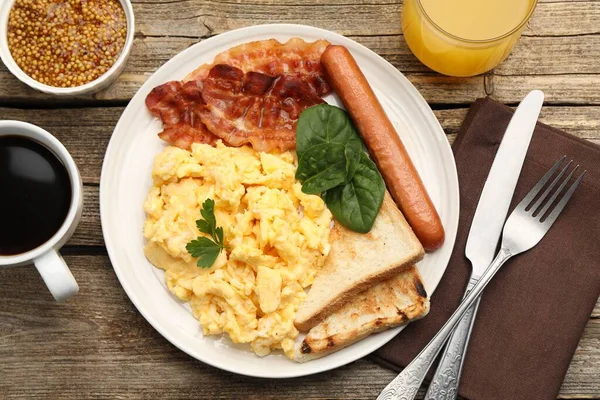 Lezzetli bir kahvaltı. Lezzetli çırpılmış yumurta, domuz pastırması ve sosis, ahşap masada servis edilir.