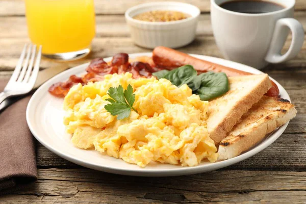 Lezzetli bir kahvaltı. Lezzetli çırpılmış yumurta, domuz pastırması ve sosis, ahşap masada servis edilir, yakın plan.