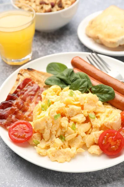 Lezzetli bir kahvaltı. Lezzetli omlet, pastırma, sosis ve domates. Gri desenli masada servis ediliyor. Yakın plan.