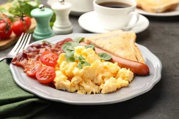 Lezzetli bir kahvaltı. Pastırmalı, sosisli ve domatesli leziz omlet. Gri desenli masada servis ediliyor. Yakın plan.
