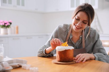 Genç bir kadın geleneksel paskalya pastasını mutfakta süslüyor. Metin için boşluk
