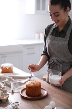 Genç bir kadın geleneksel paskalya pastasını mutfakta jöleli dekore ediyor.