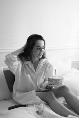 Doğum günü kutlaması. Evde yatakta nefis pastası olan bir kadın. Siyah ve beyaz etkisi