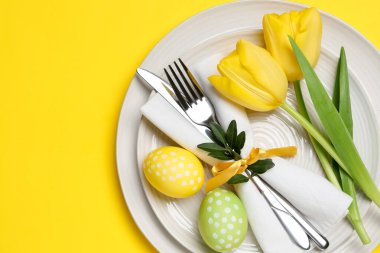 Paskalya kutlaması. Lale çiçekleri ve sarı arka planda boyanmış yumurtalar, üst manzara. Metin için boşluk