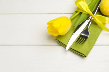 Paskalya sofrası. Beyaz ahşap arka planda laleli ve boyalı güzel gümüş takımlar, yakın plan. Metin için boşluk