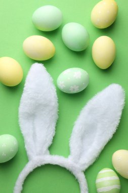Mutlu Paskalyalar. Şirin tavşan kulakları ve yeşil arka planda boyanmış yumurtalar.