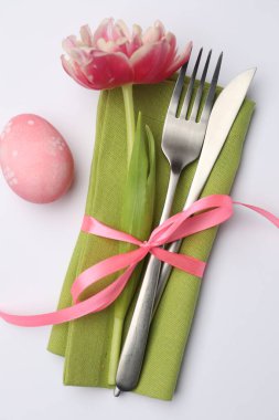 Paskalya sofrası. Beyaz arka planda lale ve boyalı yumurta ile güzel gümüş takımlar, üst manzara.