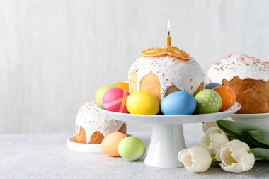 Lezzetli Paskalya pastaları, açık gri masada boyanmış yumurta ve laleler, metin için yer.