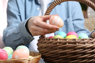 Paskalya sepetinde yumurta boyalı bir kadın, kapalı bir masada, yakın plan.