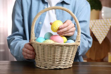 Paskalya sepetinde boyanmış yumurtalı bir kadın, kapalı masa, yakın plan.