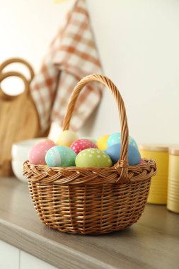 Paskalya sepetinin içinde ahşap masa üzerine boyanmış yumurtalar.