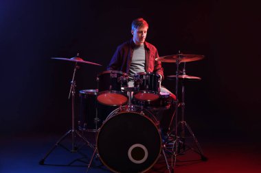 Siyah arkaplana karşı renk ışıklarıyla davul çalan adam