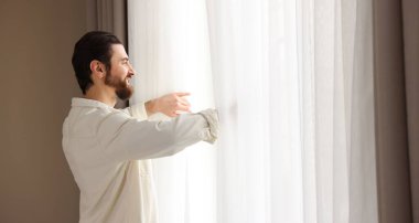 Evde şık pencere perdeleri açan adam
