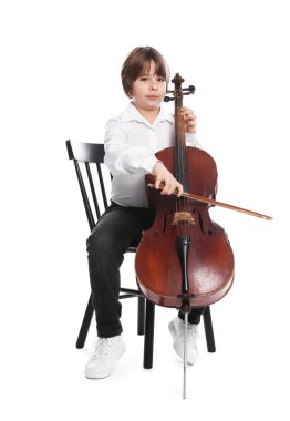 Küçük çocuk beyaz arka planda sandalyede keman çalıyor.