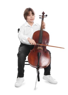 Küçük çocuk beyaz arka planda sandalyede keman çalıyor.