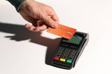 Kredi kartı olan bir adam beyaz arka planda ödeme terminalini kullanıyor.
