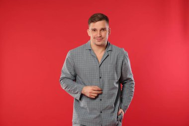 Kırmızı arka planda şık pijamalı bir adam.