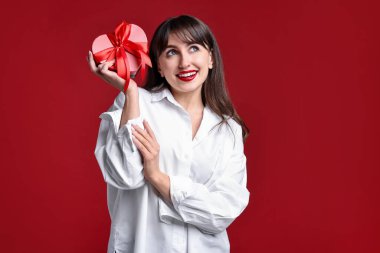 Sevgililer Günü kutlaması. Kırmızı arka planda hediye kutusu olan kadın.