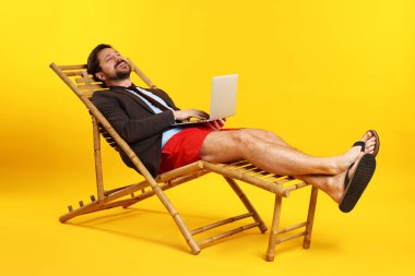 Turuncu arka planda dizüstü bilgisayarı olan bir ofis çalışanı.