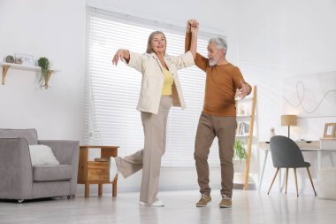Mutlu yaşlı çift evde dans ediyor.