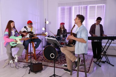 Gençlik bandosu içeride müzik öğretmeniyle performans çalışması yapıyor.