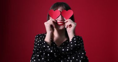 Sevgililer Günü kutlaması. Kırmızı arka planda dekoratif kalpleri olan mutlu bir kadın.
