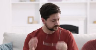 Evdeki kanepede bitkin hisseden mutsuz bir adam.