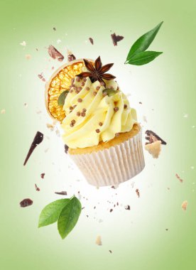 Yeşil eğimli arka planda havada uçuşan kremalı lezzetli kek.