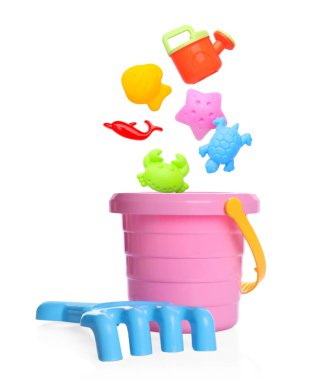 Çocuklar için plaj oyuncakları. Plastik kum kalıpları ve sulama kutusu beyaz arka planda kovaya düşer.
