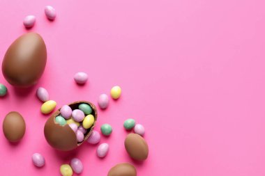 Pembe arka planda şekerli, çikolatalı Paskalya yumurtaları. Metin için boşluk