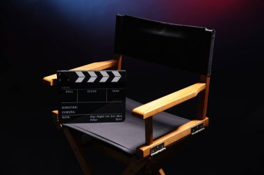 Film yönetmeninin sandalyesi. Koyu arkaplanda, neon lambalı, yakın plan.