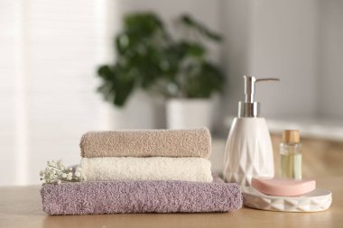 Temiz havlu yığını, çingene çiçekleri ve kozmetik ürünleri kapalı masa, yakın plan.