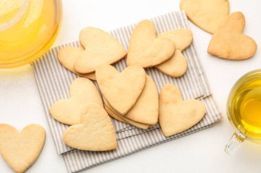 Lezzetli kalp şeklinde tereyağlı kurabiye ve çay beyaz masada, düz yerde.