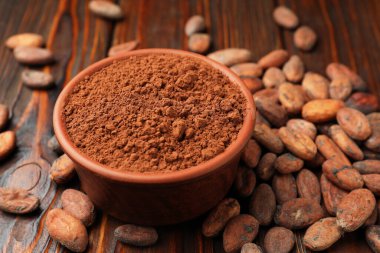 Doğal kakao çekirdeği ve toz tahta masanın üzerinde, yakın plan.