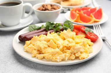 Lezzetli bir kahvaltı. Lezzetli çırpılmış yumurta, sosis ve domatesler gri desenli masa, yakın plan.