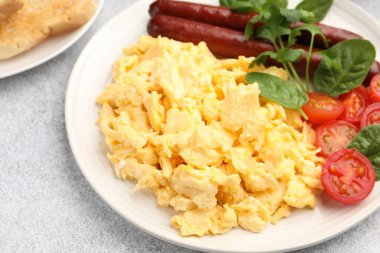 Lezzetli bir kahvaltı. Sosisli, domatesli, fesleğenli ve maydanozlu lezzetli omlet. Gri desenli masa, yakın plan.