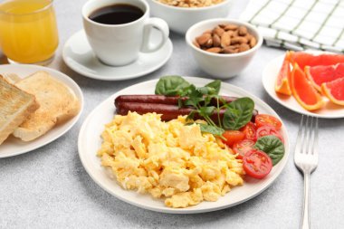 Lezzetli bir kahvaltı. Lezzetli çırpılmış yumurta, sosis ve domatesler gri desenli masa, yakın plan.
