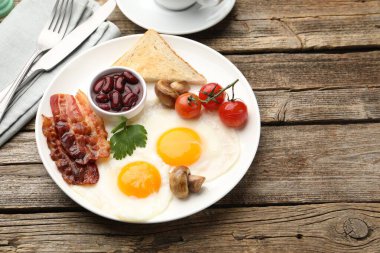 Geleneksel İngiliz kahvaltısı. Lezzetli, güneşli tarafı domuz pastırması, kırmızı fasulye, domates, mantar ve ahşap masada servis edilen kızarmış ekmek, yakın plan. Metin için boşluk