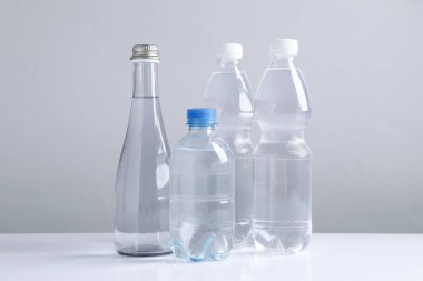 Beyaz masada gri arka planda farklı boyutlarda su şişeleri