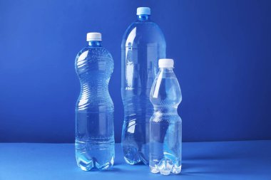 Mavi arka planda farklı boyutlarda su şişeleri