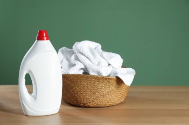 Ahşap masa üzerinde havlular ve deterjan olan çamaşır sepeti koyu yeşil arka plan, metin için boşluk