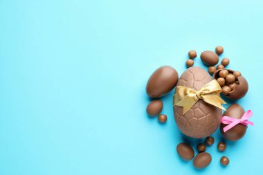 Çikolatalı Paskalya yumurtaları, şekerli ve fiyonklu açık mavi arka plan, düz. Metin için boşluk