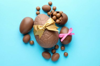 Çikolatalı Paskalya yumurtaları, şekerli ve fiyonklu açık mavi arka plan, düz uzanmış.