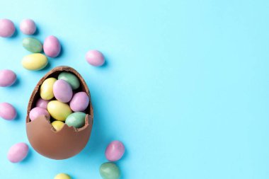 Paskalya kutlaması. Açık mavi arka planda şekerli kırık çikolata yumurtası, düz. Metin için boşluk