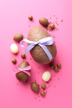 Çikolatalı Paskalya yumurtaları pembe arka planda şekerli, düz yatıyordu.