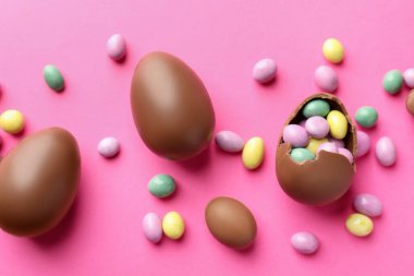 Çikolatalı Paskalya yumurtaları pembe arka planda şekerli, düz yatıyordu.