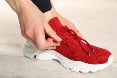 Kırmızı spor ayakkabı bağcığı bağlayan kadın, yakın plan.