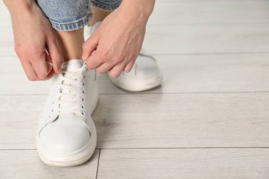 Beyaz spor ayakkabı bağcığı bağlayan kadın, yakın plan. Metin için boşluk