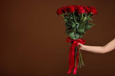 Sevgililer Günü kutlaması. Kahverengi arka planda gül buketi olan kadın, yakın plan. Metin için boşluk